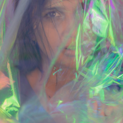sithara looking at camera wrapped in iridescent plastic